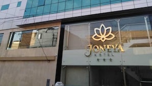 A modern hotel building with a glass facade and a logo of a lotus flower above the entrance.