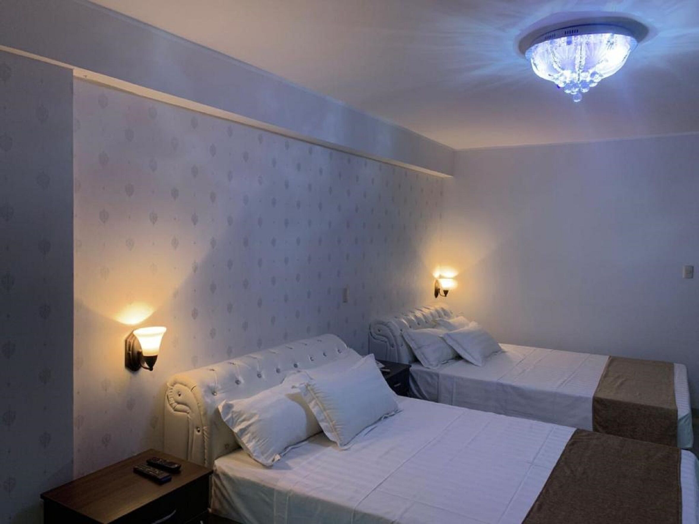 Une chambre d’hôtel avec deux lits, une table de chevet et un lustre.