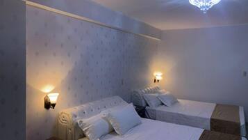 Une chambre d’hôtel avec deux lits, une table de chevet et un lustre.