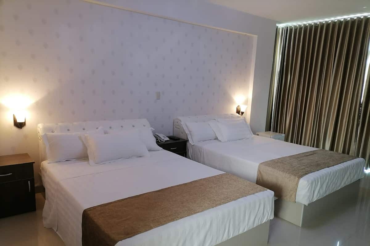 Une chambre d’hôtel avec deux lits, une table de chevet avec un téléphone et un rideau.
