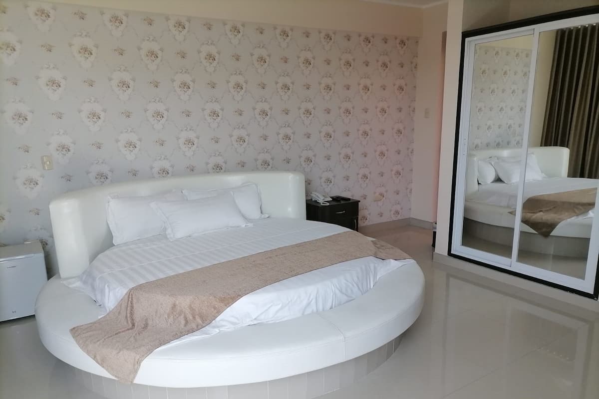 Une chambre moderne avec un grand lit, une table de chevet, un miroir et une armoire.