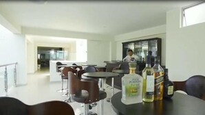 A modern dining area with a long table, chairs, and a bar area with bottles. - Joneya Hotel (Chiclayo)