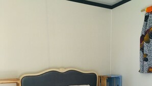 A single bed with a wooden frame, white bedding, and a brown blanket. There is a small blue shelf unit to the right of the bed. - Chalet Le Coquet, cozy n'est surrounded by greenery - Naturist area (Collonges-la-Rouge)