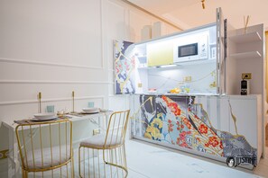 Une cuisine moderne équipée d’un four à micro-ondes, d’un évier et d’un crédence décorative. On y trouve deux chaises et une table à manger.