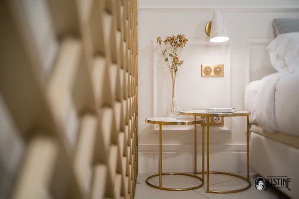 Une chambre à coucher moderne, avec un lit, des tables de chevet, une lampe fixée au mur et un vase décoratif.