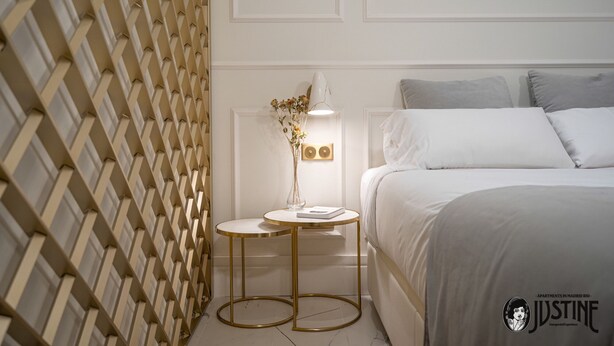 A bedroom with a bed, bedside table, lamp, and decorative vase.