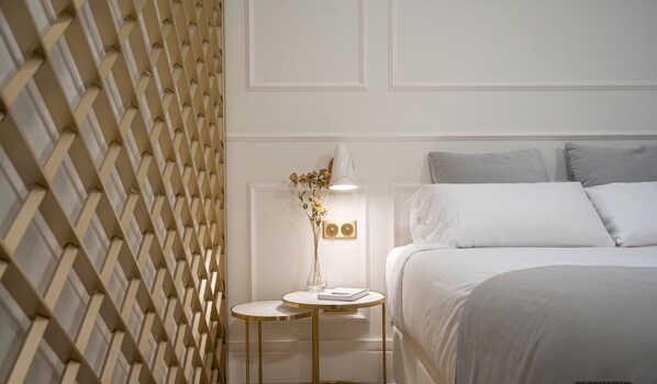 A bedroom with a bed, bedside table, lamp, and decorative vase.