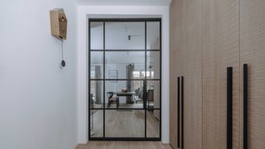 A modern interior with a sliding glass door leading to a dining area, a wooden floor, and a minimalist wall design. - Apartment SeeSuite 2 (Rottach-Egern)
