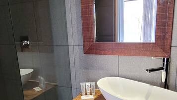 Un baño con tocador de madera, lavamanos blanco y espejo grande.
