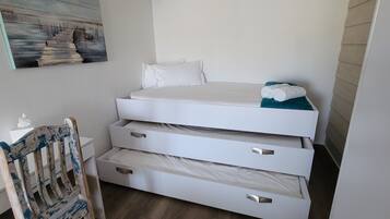 Un dormitorio pequeño con cama, una silla y una obra de arte colgada en la pared.