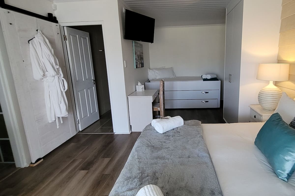 A bedroom with a bed, bedside table, lamp, and a wardrobe.