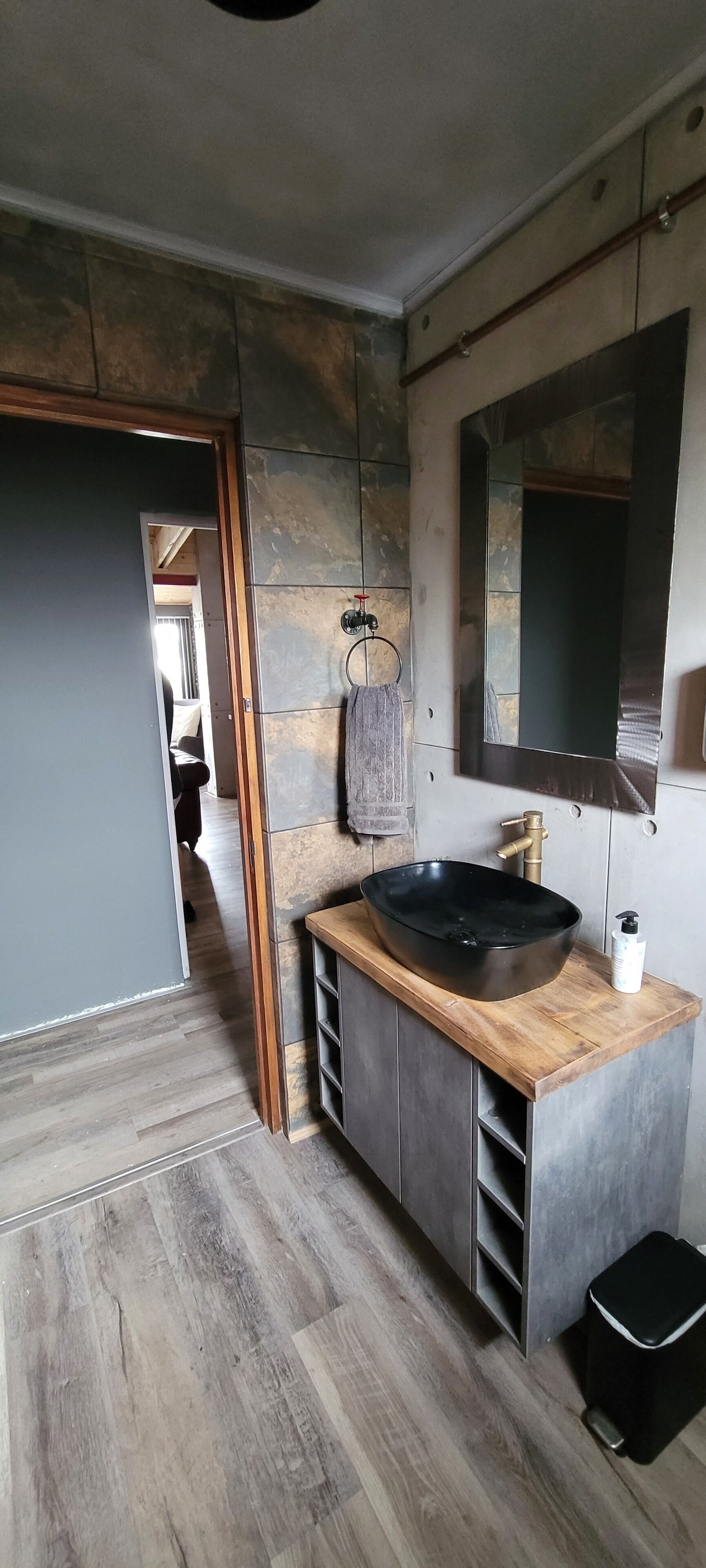 Un baño moderno con un lavamanos negro grande, un espejo y una toalla colgada en la pared.