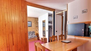 Un interior de madera con una mesa de comedor, sillas, un sofá y una zona de cocina.