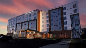 A Courtyard by Marriott hotel with a modern design, multiple floors, and a well-lit entrance. - Courtyard by Marriott Indianapolis Fishers (Fishers)
