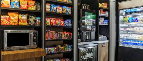 A self-service snack and beverage area with a microwave, refrigerated drinks, and a coffee machine.
