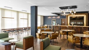 A modern restaurant with round tables and chairs, a bar area, and a seating area with sofas and chairs. - Courtyard by Marriott Indianapolis Fishers (Fishers)