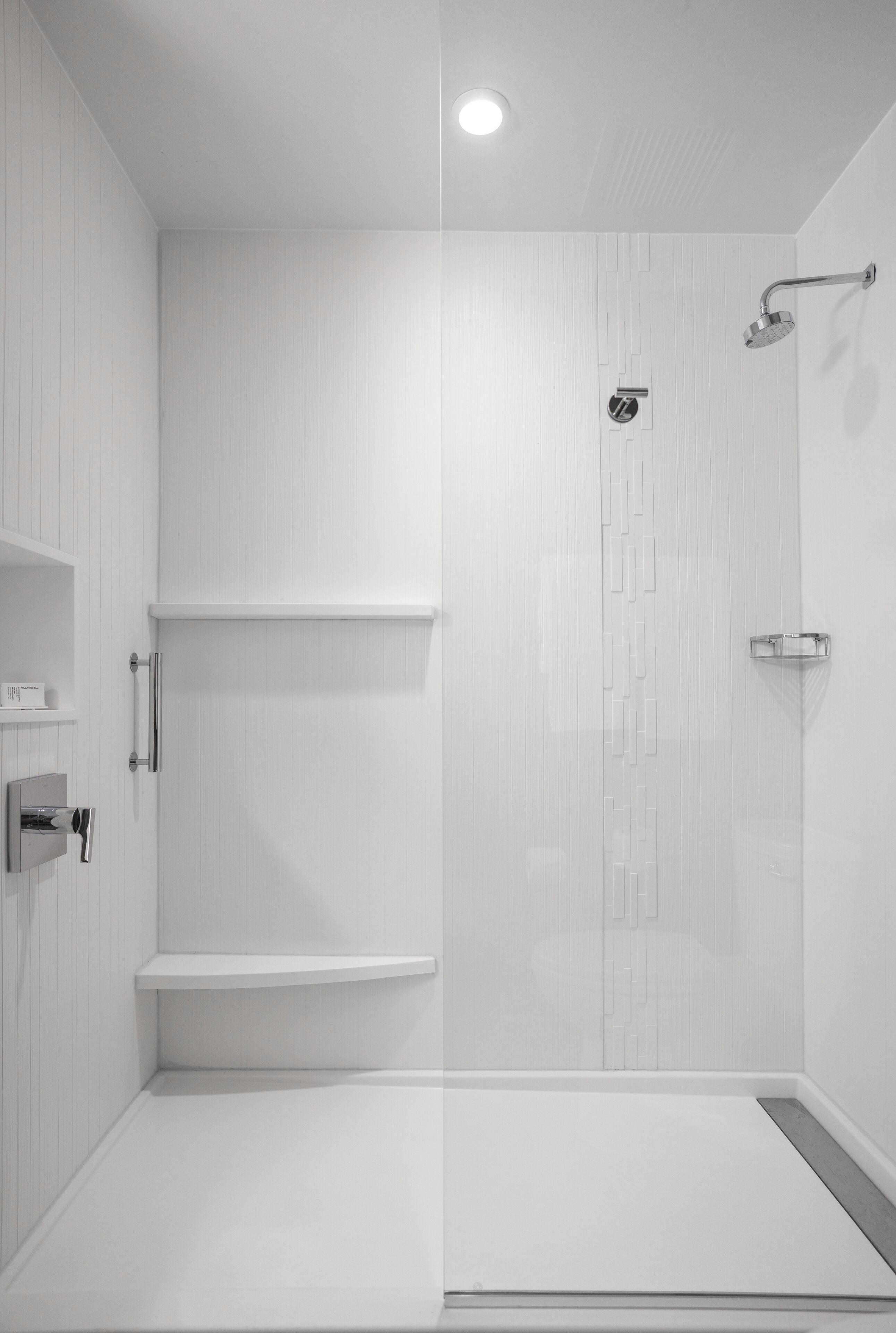 A modern, empty bathroom with white walls, a shower area, and a toilet.