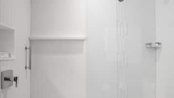 A modern, empty bathroom with white walls, a shower area, and a toilet.