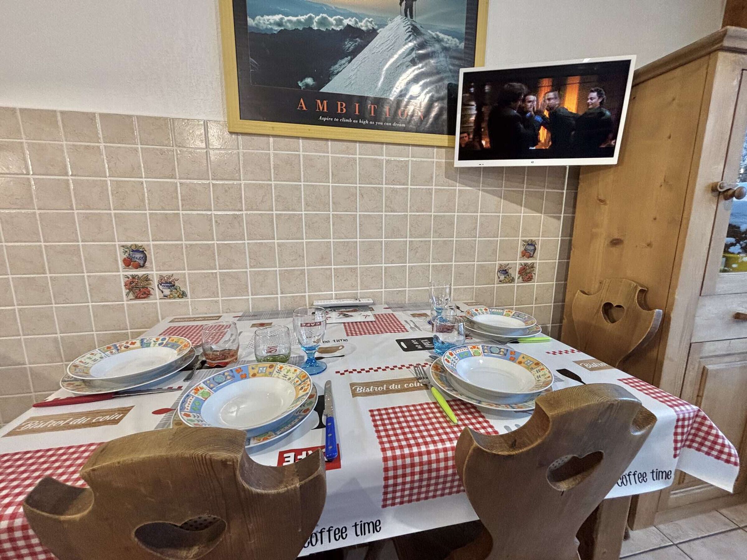 Una mesa de comedor dispuesta con platos, vasos y cubiertos, cubierta con un mantel a cuadros.