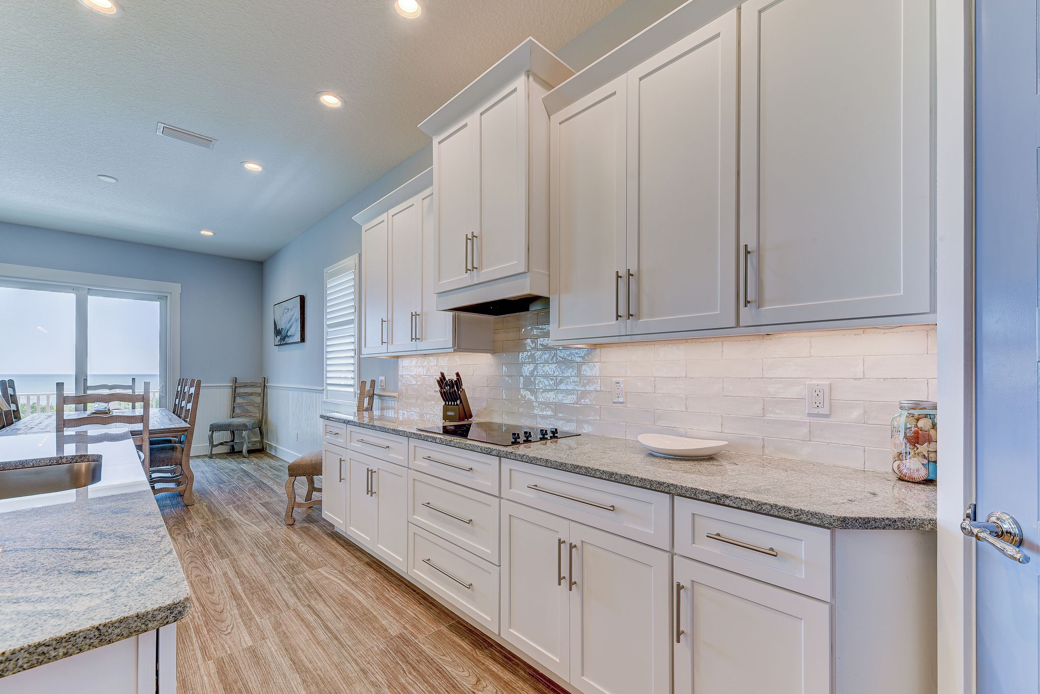 A modern kitchen with white cabinets, granite countertops, and a large island.
