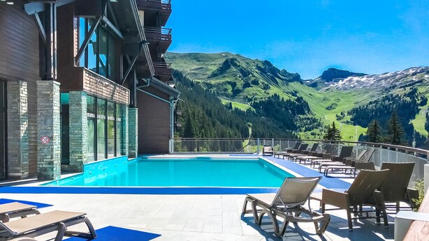 Poolbereich mit Liegestühlen und Bergblick.