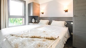 A bedroom with a large bed, two bedside lamps, a nightstand, and a wardrobe. - South-facing newly renovated 2-bed apartment (Flaine)