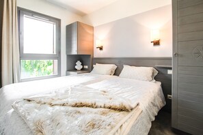 A bedroom with a large bed, two bedside lamps, a nightstand, and a wardrobe.