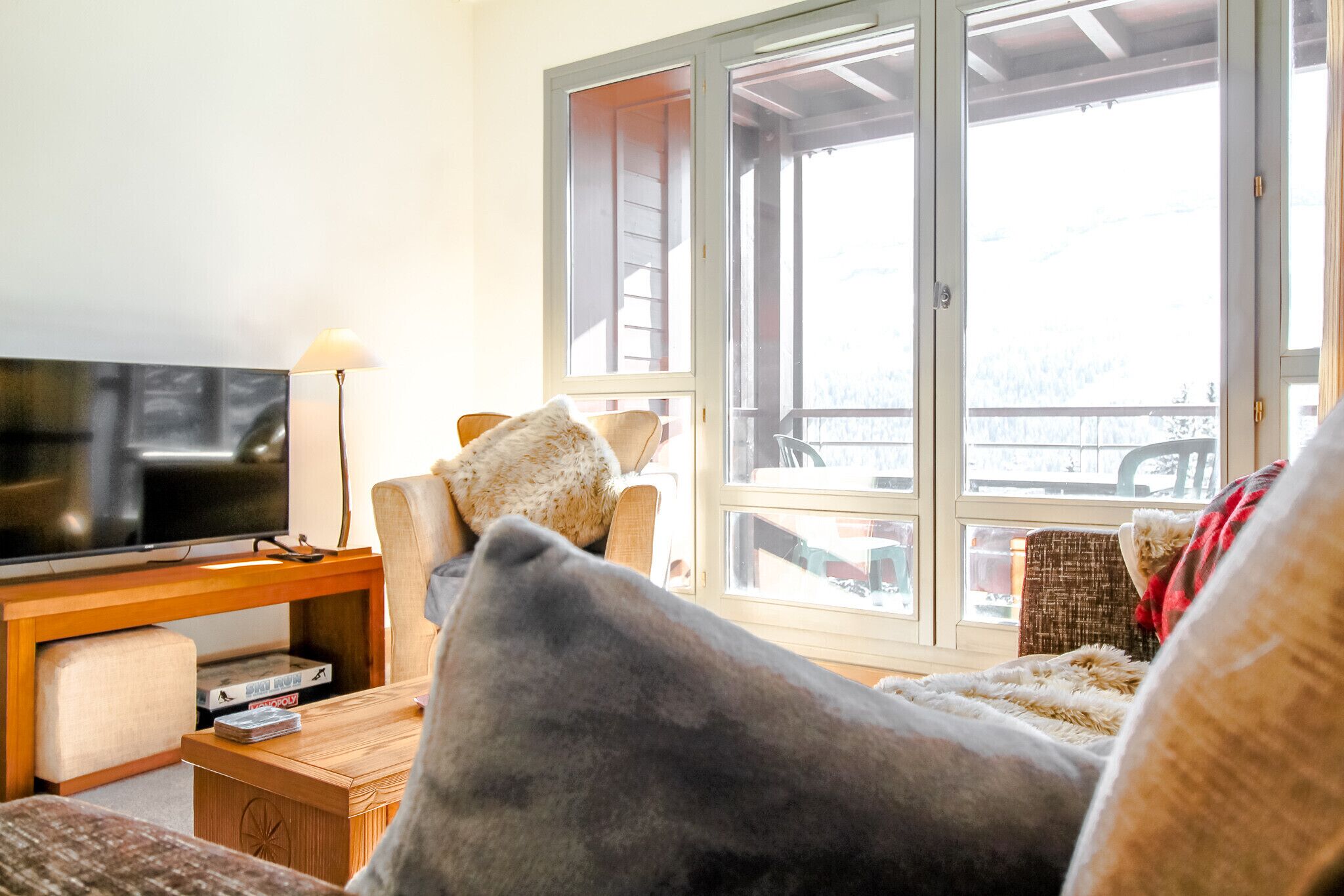 Sala de estar com televisão, móveis de madeira e uma grande janela com vista.