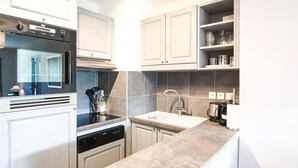 A modern kitchen with stainless steel appliances, a dishwasher, a sink, and a coffee maker. - South-facing newly renovated 2-bed apartment (Flaine)