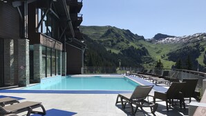 A pool area with lounge chairs and a view of mountains. - South-facing newly renovated 2-bed apartment (Flaine)