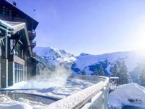 Un paisaje montañoso cubierto de nieve con un edificio que tiene ventanas grandes y un balcón.