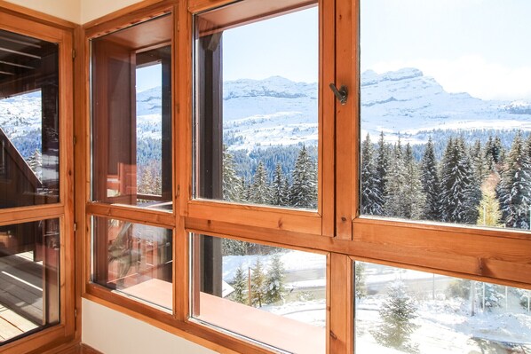 A room with large windows offering a view of snow-covered mountains and trees.