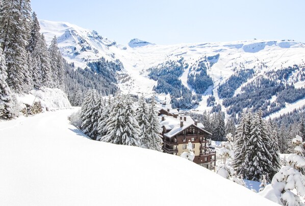 A snow-covered mountain landscape with a lodge featuring multiple floors and a ski slope in the background.