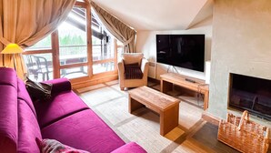 Una sala de estar moderna con un televisor grande, un sofá, una mesa de centro y una chimenea.