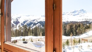 A room with a large window offering a view of a snowy mountain landscape. - Two internally connecting 2-bed apartments with shared private entrance (Flaine)