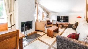 A spacious living room with a fireplace, sofas, a TV, and a wooden coffee table. - Two internally connecting 2-bed apartments with shared private entrance (Flaine)