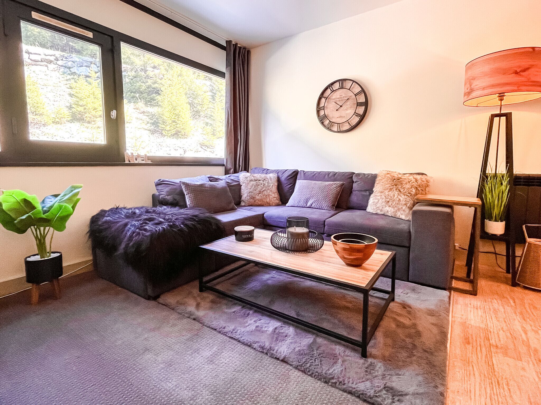 A modern living room with a sofa, a coffee table, a lamp, and a clock on the wall.