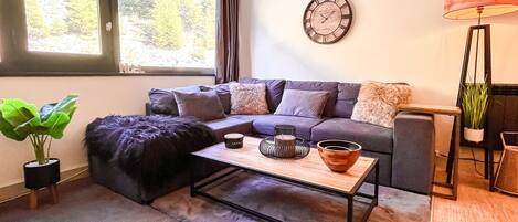 A modern living room with a sofa, a coffee table, a lamp, and a clock on the wall.