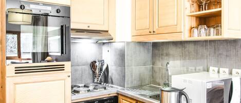 A kitchen with wooden cabinets, stainless steel appliances, and a microwave.