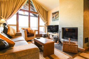 Ein gemütliches Wohnzimmer mit Sofa, Couchtisch, Fernseher und Kamin.