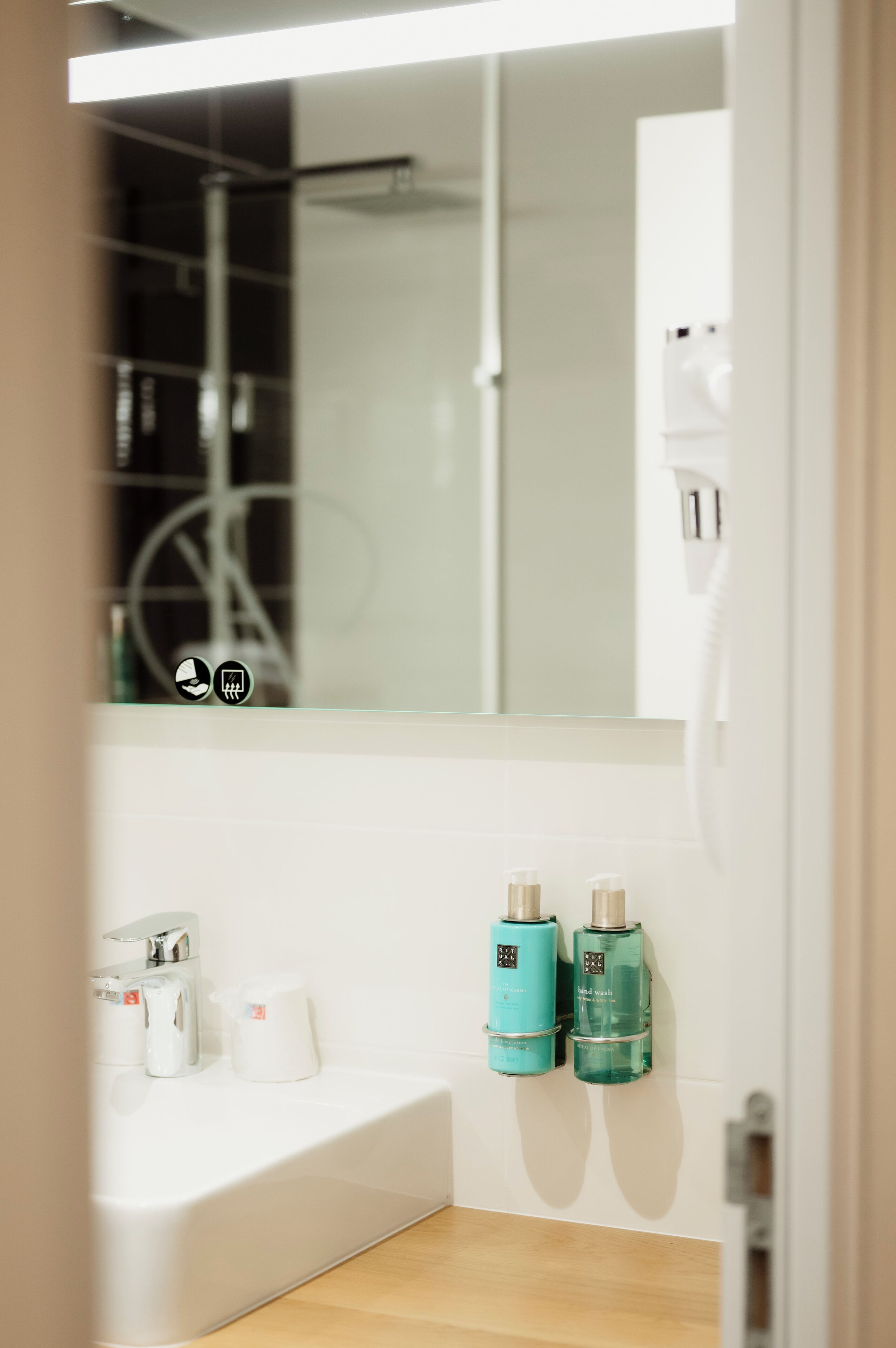 A bathroom with a white sink, two bottles of liquid soap, and a mirror above the sink.