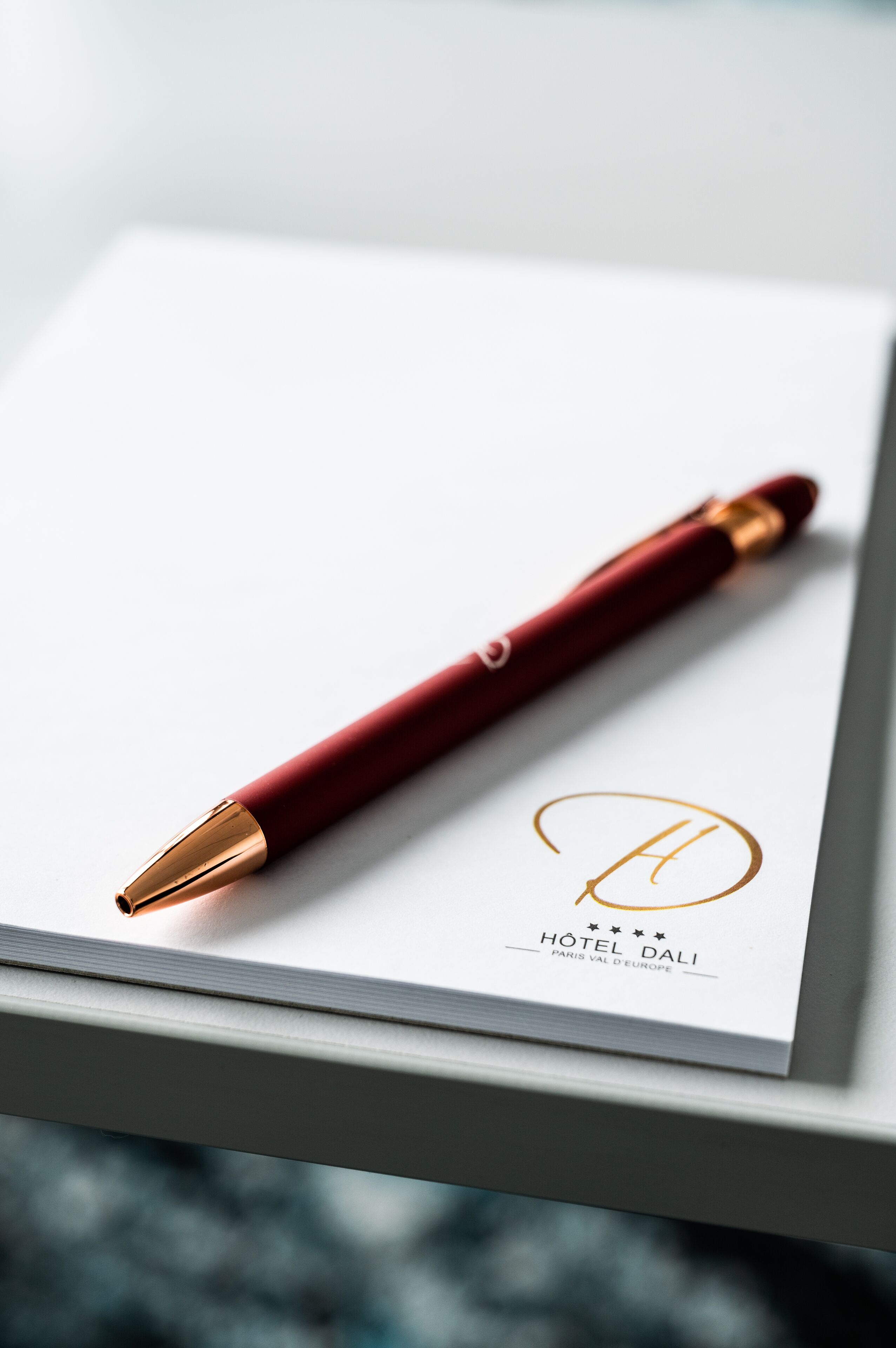 En rød pen på et hvidt kort med Hotel Dali logo og navn.