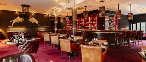 Un restaurante con mesas redondas, sillas de cuero y una alfombra roja.