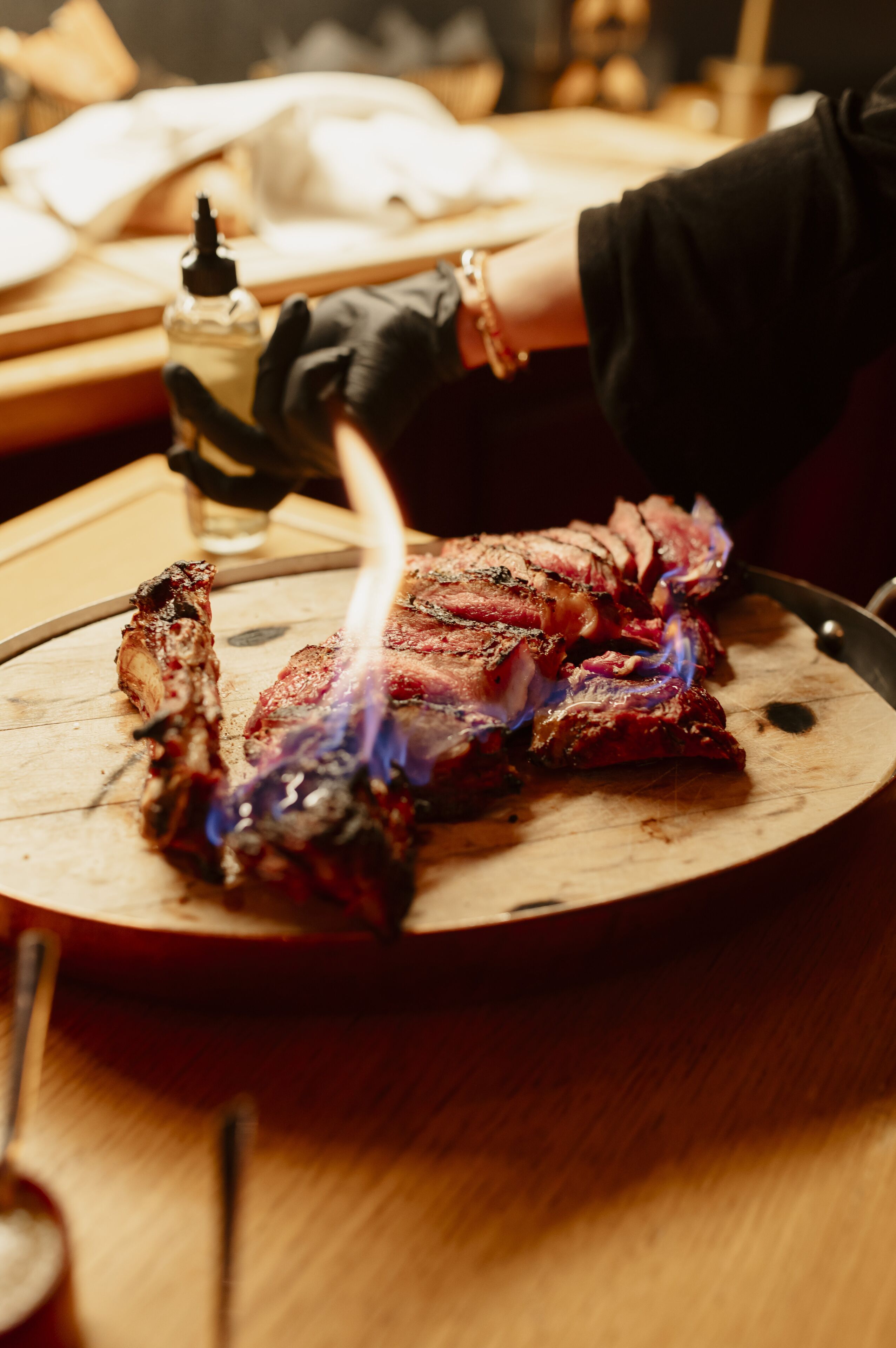 Una persona asando un bistec sobre una tabla de madera.