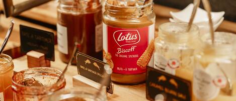 A variety of jars and containers with labels, likely containing food items or condiments, arranged on a wooden surface.