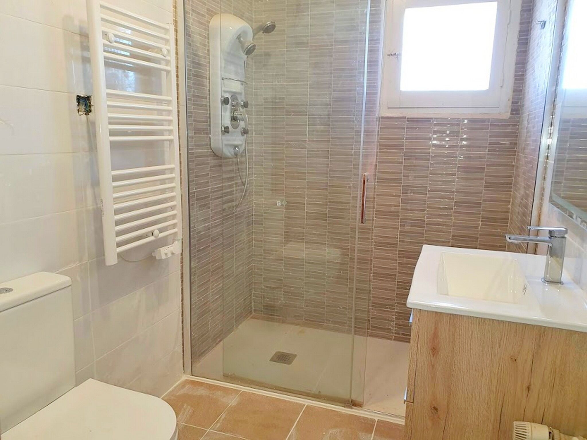 Une salle de bain avec une douche à parois de verre, un lavabo blanc et des toilettes.