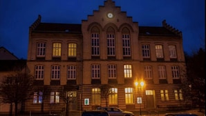 Een groot, historisch gebouw met een klokkentoren, gebogen ramen en een symmetrische gevel.