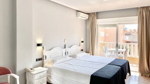 A hotel room with a large bed, a bedside table with a phone, a chair, and a balcony with a table and chairs. - HOTEL PARQUE MAR (Guardamar del Segura)