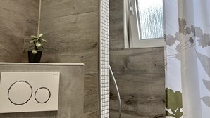 Un bany modern amb parets de fusta, una dutxa amb porta de vidre i una finestra que deixa entrar llum natural.