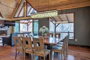 Un comedor amplio con una gran mesa de madera, varias sillas y un candelabro.